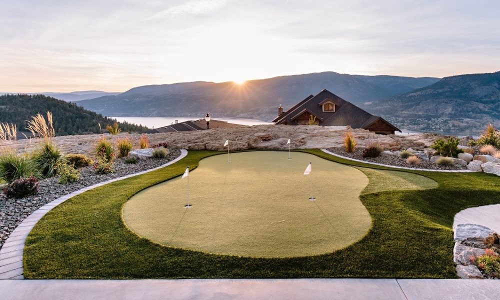 Turf putting green overlooking a sunset and the mountains